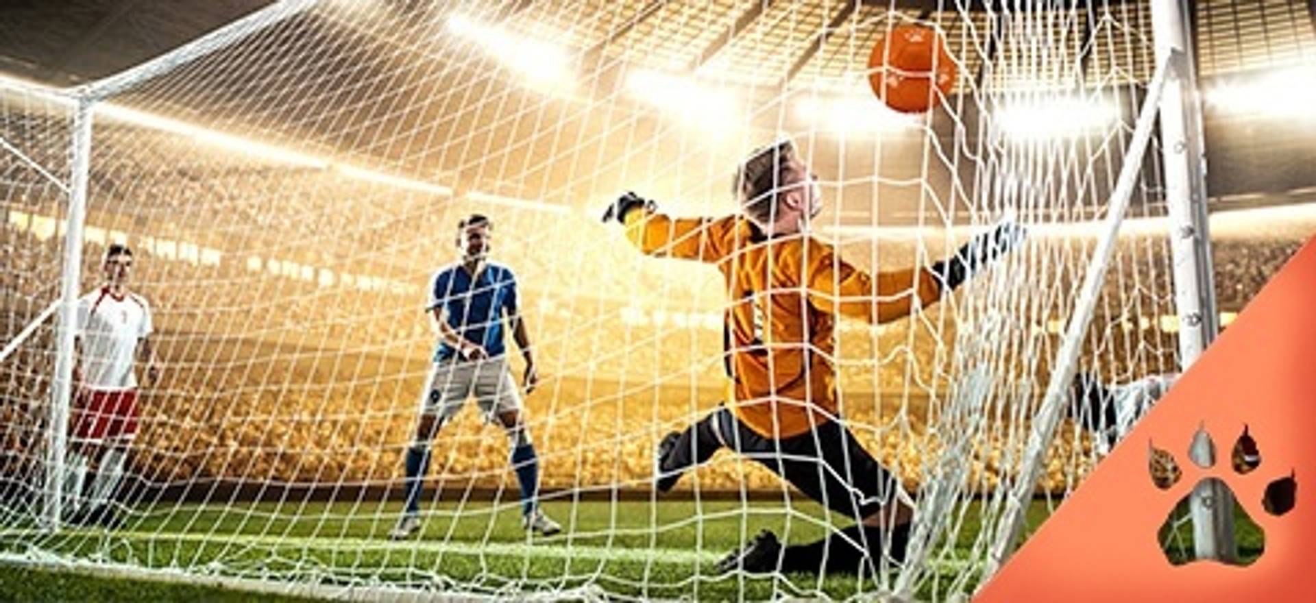 Portero de fútbol intentando parar un balón durante un partido en un estadio.